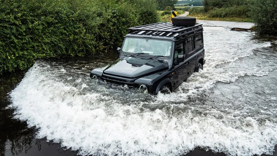 A 2025 Ineos Grenadier fording a water crossing on the trail